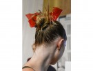 Un’idea semplice e veloce? Uno chignon alto e spettinato, con un fiocco rosso in… cellophane, riciclando le confezioni dei regali natalizi.