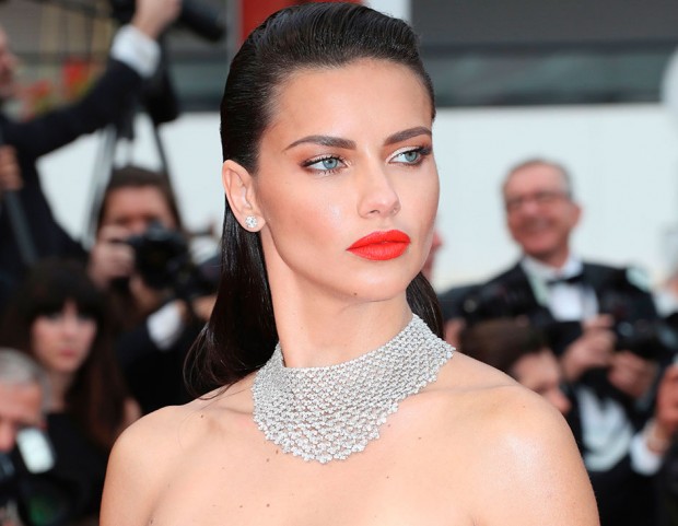 Punta tutto sulle labbra Adriana Lima, con un rossetto rosso aranciato incandescente. (Photo credit: Getty Images)