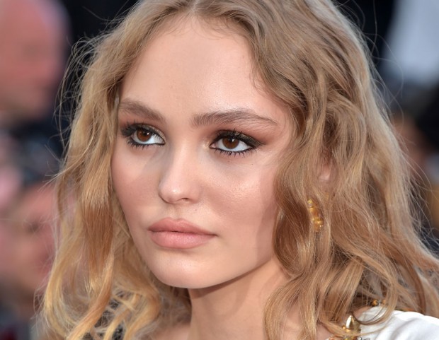 L’incarnato glowing di Lily-Rose Depp viene esaltato da occhi intensi con smokey eyes e kajal, in abbinamento a un rossetto beige opaco. (Photo credit: Getty Images)