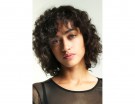 Capelli ricci con taglio medio e frangia.
