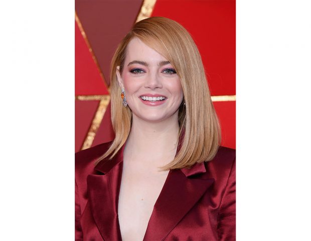 Make up nei toni del rosa e acconciatura liscia con riga laterale per Emma Stone. (Photo credit: Getty Images)