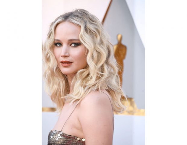 Smokey eyes, rossetto mattone e mosso vaporoso per Jennifer Lawrence. (Photo credit: Getty Images)