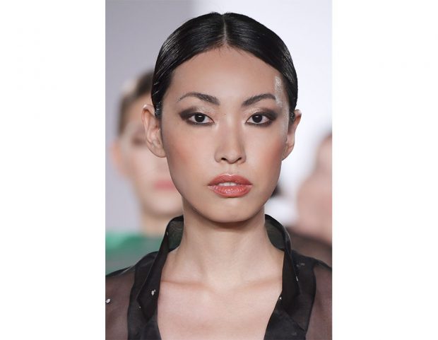 Acconciatura sleek, con scriminatura centrale e radici flat.