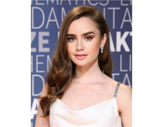Acconciatura laterale per Lily Collins con onde sulle punte. Photo credit: Getty Images